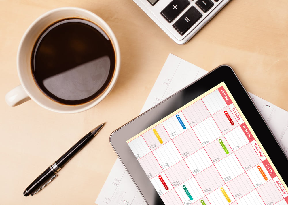 Tablet showing calendar alongside coffee and pen